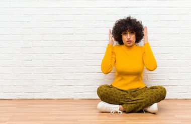 Genç, güzel afro kadın şok olmuş ve afallamış görünüyor, yere oturan inanılmaz bir şey fark edince çenesi şaşkın ve şaşkın