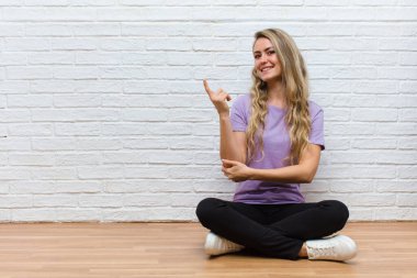 Genç sarışın güzel kadın mutlu bir şekilde gülümsüyor ve yan bakıyor, merak ediyor, düşünüyor ya da bir fikri var.