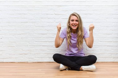 Genç sarışın güzel kadın mutlu, şaşırmış ve gururlanmış hissediyor, bağırıyor ve başarıyı büyük bir gülümsemeyle kutluyor.