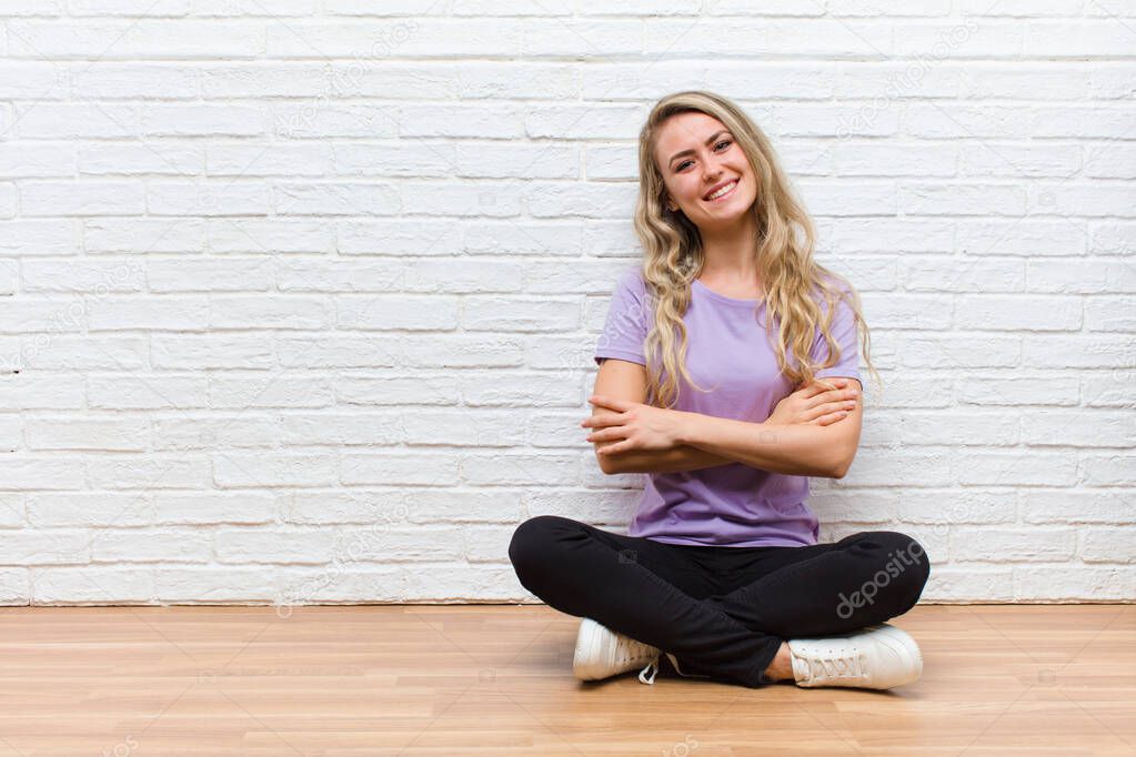 young blonde pretty woman laughing happily with arms crossed, with a relaxed, positive and satisfied pose