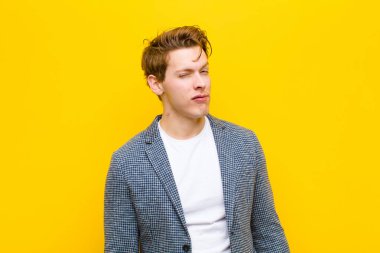 Genç kızıl saçlı adam mutlu ve arkadaş canlısı görünüyor, gülümsüyor ve turuncu arka plana karşı pozitif bir tavırla sana göz kırpıyor