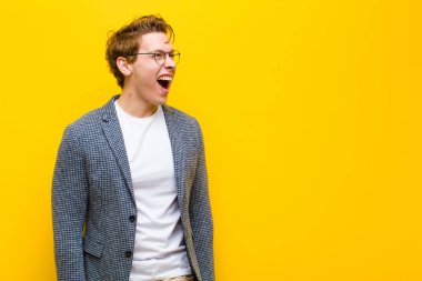 Genç kızıl saçlı adam öfkeyle bağırıyor, saldırganca bağırıyor, stresli ve sinirli görünüyor.