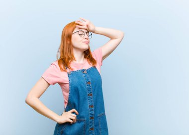 Genç kızıl saçlı güzel kadın stresli, yorgun ve hayal kırıklığına uğramış, alnından ter damlayan, umutsuz ve bitkin hisseden.