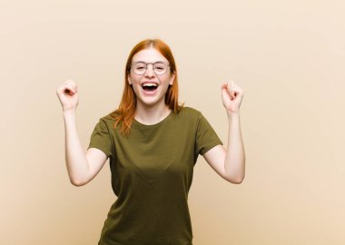 Genç kızıl saçlı güzel bir kadın mutlu, şaşırmış ve gururlu, bağırıyor ve başarıyı büyük bir gülümsemeyle kutluyor.