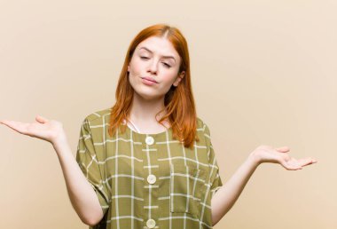 Genç kızıl saçlı güzel kadın şaşkın, kafası karışmış ve stresli görünüyor, farklı seçenekler arasında merak ediyor, kararsız hissediyor.