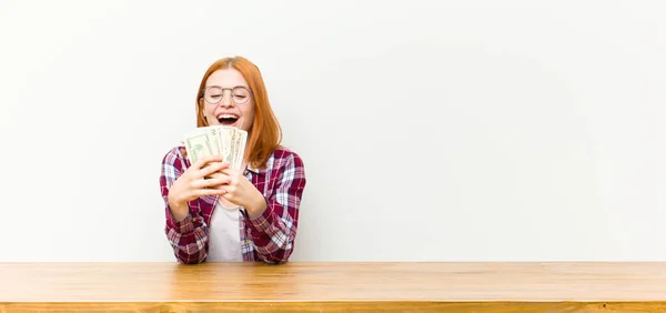 Ung Röd Huvud Vacker Kvinna Framför Ett Träbord Med Dollarsedlar — Stockfoto