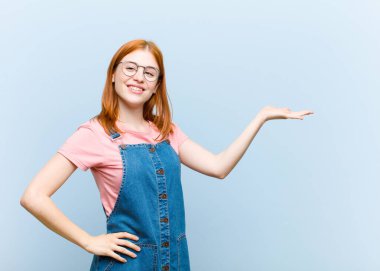 Genç kızıl saçlı güzel kadın gülümsüyor, kendinden emin, başarılı ve mutlu hissediyor, fotokopi alanında fikir veya konsept gösteriyor.