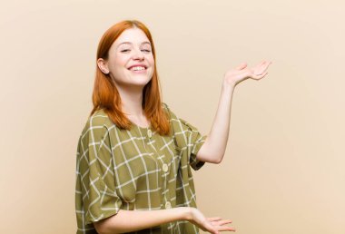 Genç kızıl saçlı güzel kadın gururla ve güvenle gülümsüyor, mutlu ve tatmin olmuş hissediyor ve fotokopi alanında bir konsept gösteriyor.