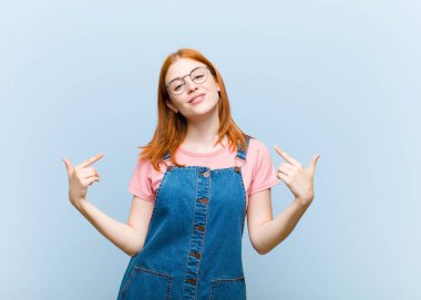 Genç kızıl saçlı güzel bir kadın gururlu, kibirli, mutlu, şaşırmış ve tatmin olmuş görünüyor.