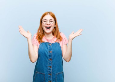 Genç kızıl saçlı güzel kadın mutlu, heyecanlı, şaşırmış ya da şok olmuş hissediyor, gülümsüyor ve hayrete düşüyor.