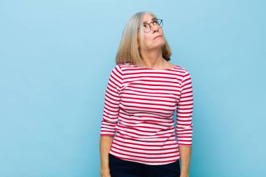 Yaşlı ya da orta yaşlı, endişeli, kafası karışık, budala bir yüzü olan, kopya alanı arayan, şüpheci bir kadın.