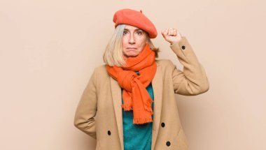 Yaşlı ya da orta yaşlı güzel bir kadın ciddi, güçlü ve asi hissediyor, yumruğunu kaldırıyor, protesto ediyor ya da devrim için savaşıyor.