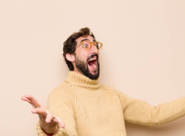 Genç, havalı bir adam neşeyle gülümsüyor sıcak, dostça, sevgi dolu bir kucaklama yapıyor, mutlu ve sevimli hissediyor düz duvara karşı.