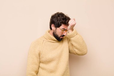 Stresli, yorgun ve hayal kırıklığına uğramış, alnından ter damlayan, umutsuz ve bitkin hisseden genç bir adam.