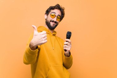 young crazy cool man with a microphone against orange wall