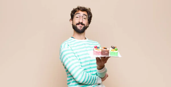 young man with a cake against flat wall