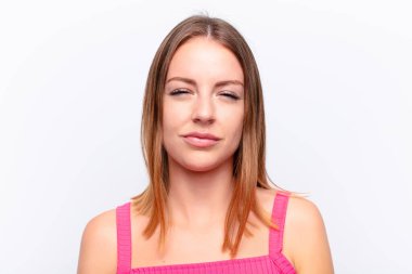 Kızıl saçlı güzel bir kadın hayal kırıklığına uğramış, hayal kırıklığına uğramış, ciddi görünüyor, kızgın ve kollarını kavuşturmuş.