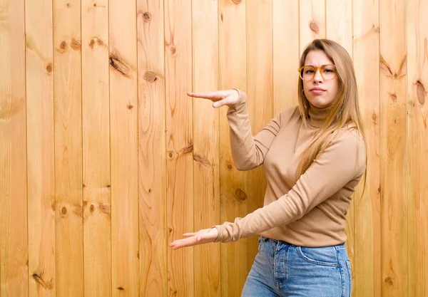 Jonge Blonde Vrouw Houdt Een Object Met Beide Handen Zijkant — Stockfoto