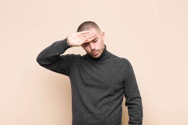 Genç yakışıklı adam stresli, yorgun ve hayal kırıklığına uğramış görünüyor, alnından ter damlıyor, umutsuz ve bitkin hissediyor.