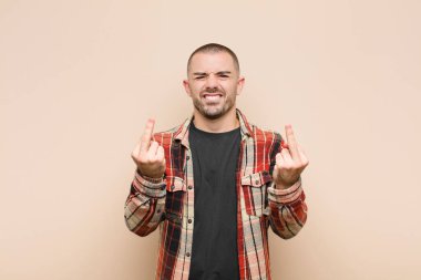 Genç yakışıklı adam kışkırtıcı, agresif ve müstehcen hissediyor. Düz duvara karşı isyankar bir tavırla orta parmağını hareket ettiriyor.