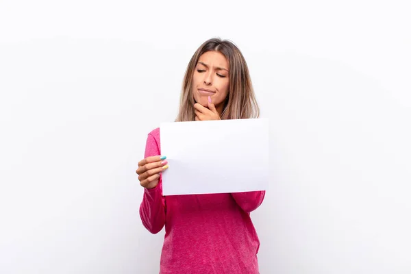 年轻漂亮的女人笑着 脸上带着快乐而自信的表情 双手托着下巴 好奇地望着旁边的标语牌 — 图库照片