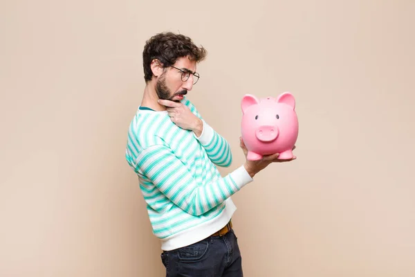 Cooler Junger Mann Hält Sparschwein Gegen Saubere Wand — Stockfoto