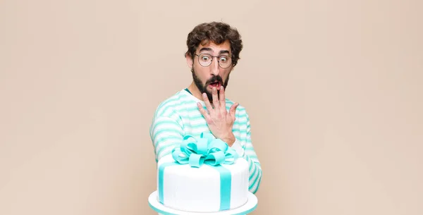 young man with a cake against flat wall