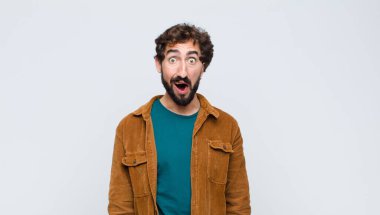 Genç yakışıklı adam korkmuş ve şok olmuş hissediyor, ağzı ardına kadar açık, düz duvara karşı şaşkınlık içinde.