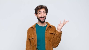 Genç yakışıklı adam kendini mutlu, şaşırmış ve neşeli hissediyor, olumlu bir tavırla gülümsüyor, düz duvara karşı bir çözüm ya da fikir buluyor.
