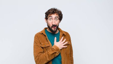 Genç yakışıklı adam şok olmuş ve şaşırmış hissediyor, gülümsüyor, el ele tutuşuyor, o olmaktan mutlu ya da düz duvara karşı minnettarlık gösteriyor.