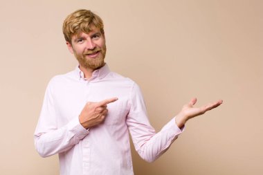 Genç, sarışın, gülümseyen, mutlu, kaygısız ve tatmin olmuş bir adam. Fotokopi odasının kenarındaki düz duvara bakan bir konsept veya fikre işaret ediyor.