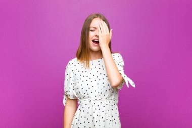 kızıl saçlı güzel kadın uykulu, sıkılmış ve esniyor, baş ağrısı ve yüzünün yarısını mor duvarla kaplayan bir el