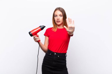 Kızıl saçlı, güzel bir kadın ciddi, sert, hoşnutsuz ve kızgın görünüyor. Avuç içi açık, elinde kuaför tutmaktan vazgeçiyor.