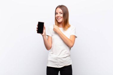 kızıl saçlı güzel bir kadın mutlu, pozitif ve başarılı hissediyor, bir meydan okumayla karşılaştığında motive oluyor veya akıllı telefon tutarak iyi sonuçları kutluyor.