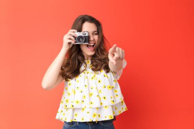 Kırmızı duvarda eski model fotoğraf makinesi olan genç ve güzel bir kadın.