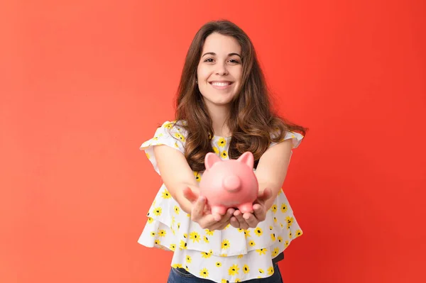 Jovem Mulher Bonita Contra Parede Vermelha Segurando Piggybank — Fotografia de Stock