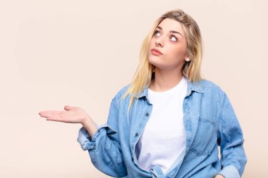 Genç, güzel sarışın kadın gülümsüyor, kendinden emin, başarılı ve mutlu hissediyor, fotokopi odasında düz duvara karşı konsept veya fikir gösteriyor.