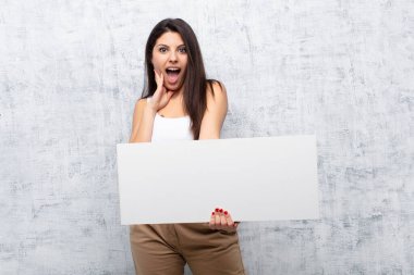 Genç ve güzel bir kadın grunge duvarına pankart asıyor.