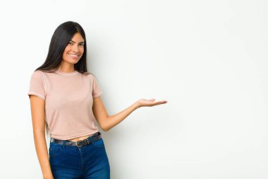 Genç, güzel Latin kadın neşeyle gülümsüyor, kendini mutlu hissediyor ve fotokopi odasında bir konsept gösteriyor.