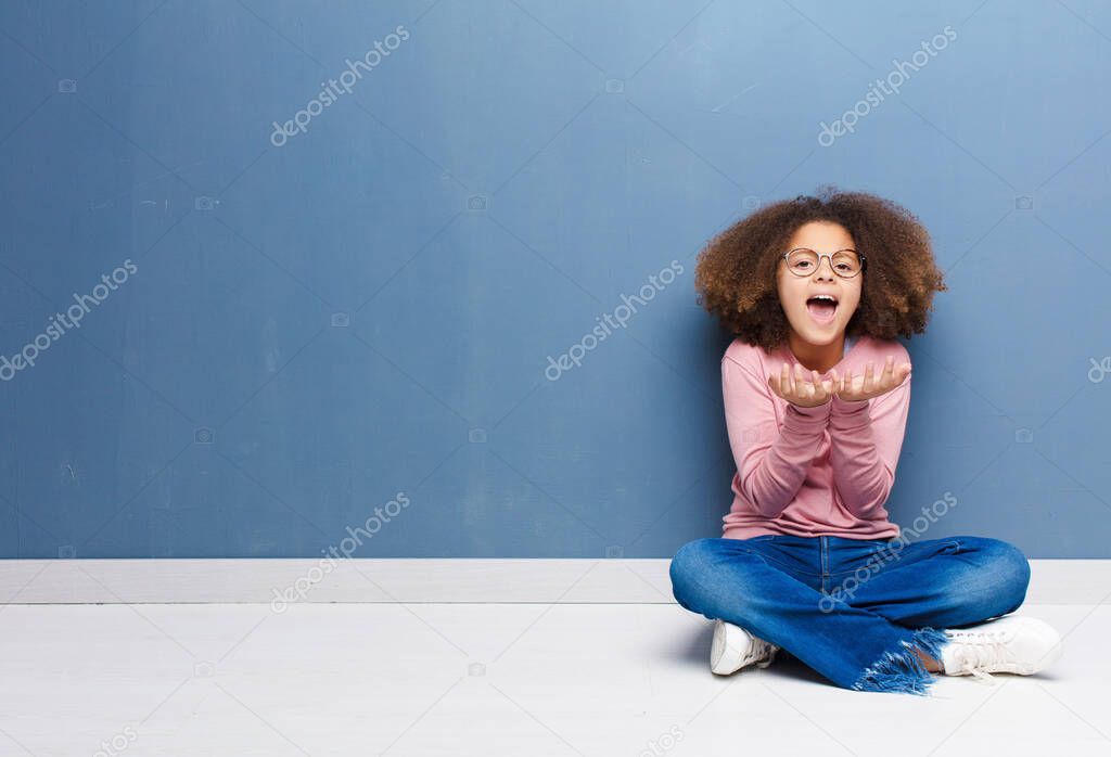 african american little girl looking desperate and frustrated, stressed, unhappy and annoyed, shouting and screaming sitting on the floor
