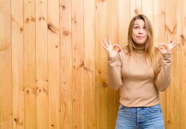 Genç sarışın kadın konsantre olmuş ve meditasyon yapıyor, kendini tatmin olmuş ve rahatlamış hissediyor, düşünüyor ya da bir seçim yapıyor.