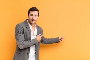 Şok olmuş ve şaşırmış hisseden bir adam, yan taraftaki fotokopi alanını açık ağızlı, şaşkın bir bakışla işaret eder.