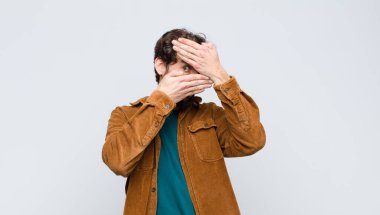 Genç yakışıklı adam kameraya hayır diyen iki eliyle yüzünü kapatıyor! Resimleri reddetmek ya da yasaklı fotoğrafları düz duvara yaslamak