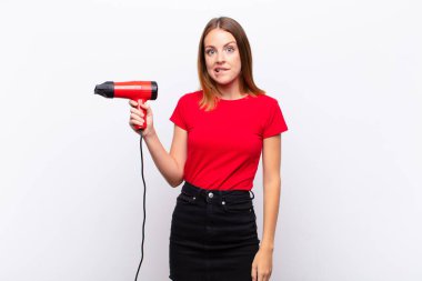 Kızıl saçlı, kafası karışmış ve kafası karışmış görünen güzel bir kadın. Gergin bir hareketle dudağını ısırıyor. Bir kuaförü elinde tutan sorunun cevabını bilmiyor.