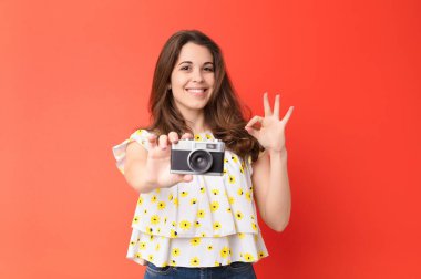 Kırmızı duvarda eski model fotoğraf makinesi olan genç ve güzel bir kadın.