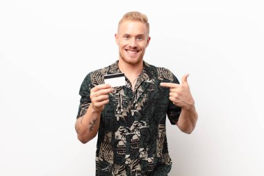 Genç sarışın adam mutlu, şaşırmış ve gururlu hissediyor. Heyecanlı ve hayret dolu bir bakışla kendini işaret ediyor.