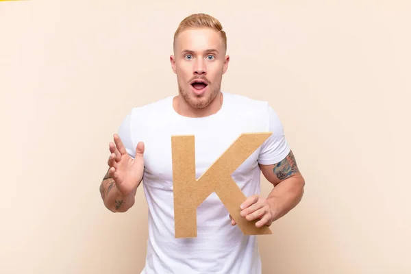 Young Blonde Man Surprised Shocked Amazed Holding Letter Alphabet Form — Stock Photo, Image