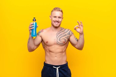 Genç sarışın güçlü bir adam konsantre olmuş ve meditasyon yapıyor, tatmin olmuş ve rahatlamış hissediyor, düşünüyor ya da enerji içeceğiyle bir seçim yapıyor.