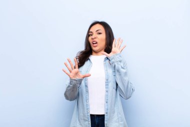 Genç Latin bir kadın korkmuş hissediyor, korku ve panik içinde geri çekiliyor ve düz duvara karşı bir kabusa tepki veriyor.