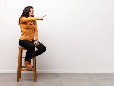 Genç, güzel bir kadın neşeyle ve tesadüfen gülümsüyor. Pozitif, mutlu ve kendinden emin bir bakışla bir odada oturuyor.